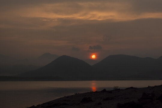 View of the sunrise over the mountains and calm lake waters in Jalapa, Oaxaca, Mexico.