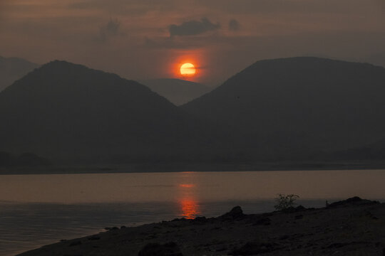 View of the sunrise over a calm lake with silhouettes of mountains in the background in Jalapa, Oaxaca, Mexico.