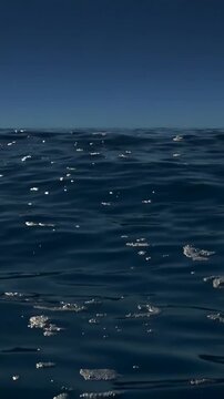 Vertical video: Drifting patches and sea surface moving at sea, current carrying, sun glinting