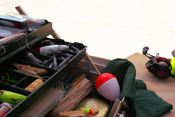 Fishing equipment and accessories are packed into a tackle box, showcasing a collection of lures and bobbers ready for an outdoor fishing adventure © Vero Dibe