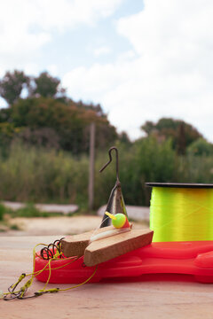 Fishing tackle and gear laying on a wooden surface with a bright yellow fishing line spool, hooks, sinker, and bobber, ready for an outdoor activity or leisure hobby