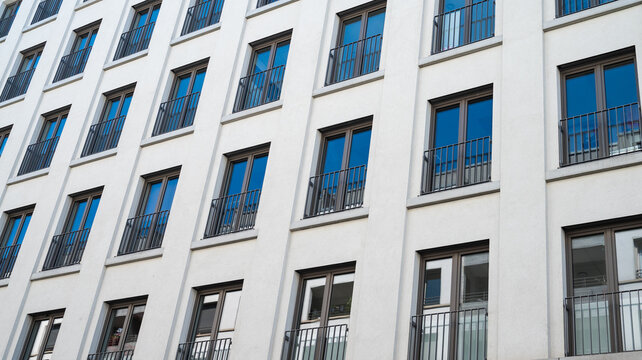 Modern white building facade with repeating windows. Minimalist urban architecture background. Perspective view of contemporary corporate or residential exterior, selective focus, shifted horizon, bac