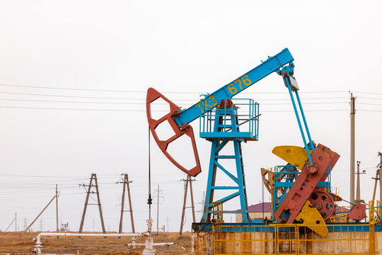 View of a blue and yellow pumpjack operating in an oil field in Zhanaozen, Mangystau Region, Kazakhstan.