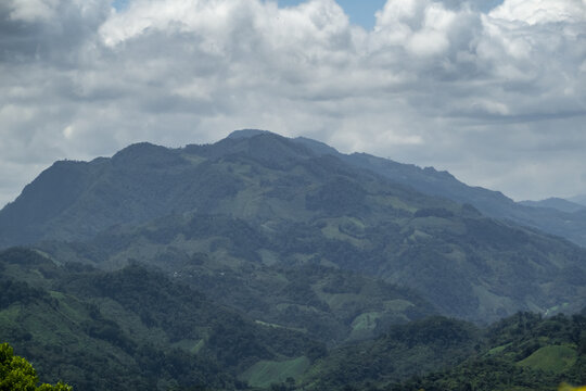 View of the lush green mountains and rolling hills of the landscape under a cloudy sky in Agua Azul, Chiapas, Mexico.