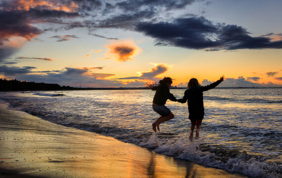 Happy children jump into the water on the beach at sunset. Gdansk, Poland