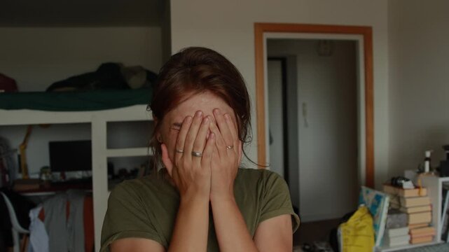 Close-up of a woman in her messy room, uncontrollably crying with a contorted face, expressing profound despair, depression, and anxiety. Raw emotion video footage