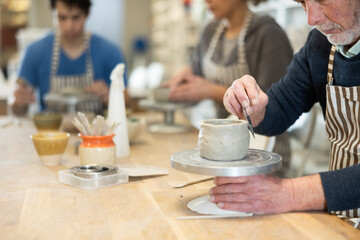 Male hands sculpting product from raw clay in ceramic workshop closeup