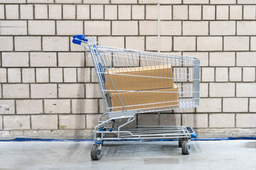 shopping cart with boxes in front of brick wall © Maria
