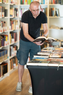 Adult male reader explores aisles of bookstore, looking for new title to enjoy