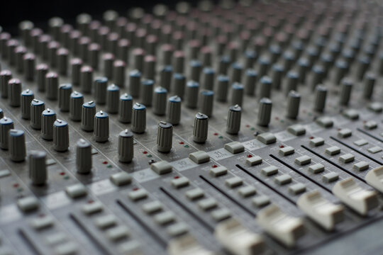 Professional audio mixing console with knobs and faders in a recording studio for music production and sound engineering.