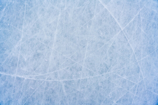 Ice background with marks from skating and hockey, blue texture of rink surface with scratches