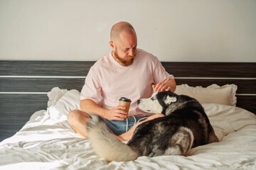 Man stroking his husky while holding a cup of coffee © iwavephoto