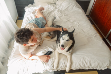 Top view of a teenage boy and a husky dog on a bed © iwavephoto