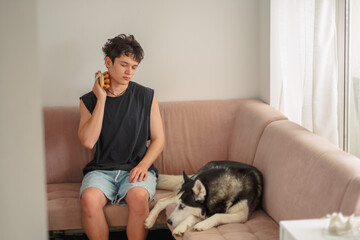 Teenage boy with a neck massager beside a sleeping husky © iwavephoto