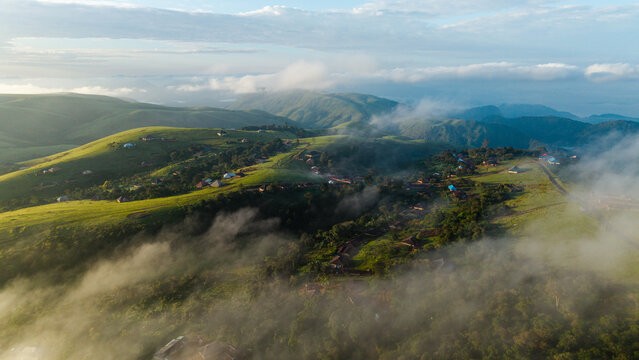Aerial view of Obudu Mountain Resort with scattered chalets nestled among lush green rolling hills and morning mist in Obudu, Cross River, Nigeria.