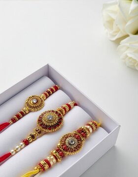 Traditional Gold and Red Rakhis in Gift Box With White Roses for Raksha Bandhan Celebration