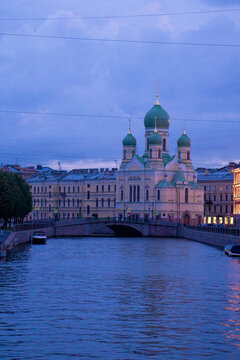 Classic historic orthodox church cathedral building facade near urban river canal at twilight blue hour.
