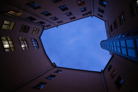 Abstract urban architecture of historic residential building courtyard view from bottom looking up at twilight sky.

