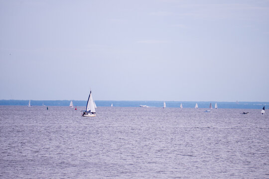 White sailing yacht sailboat floating on calm sea water at sunset evening horizon.
