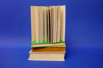 An open book stands upright with pages fanned into a fan shape for a back to school concept, resting on a closed cover against a vibrant blue background © Татьяна Швец