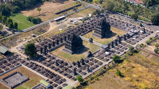 Aerial view of Plaosan Lor Temple featuring ancient stone structures and stupas surrounded by lush greenery and rural landscape in Kecamatan Prambanan, Jawa Tengah, Indonesia.