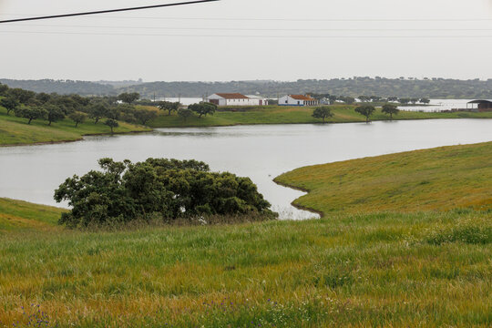 Alentejo countryside lake with farm buildings and green hills