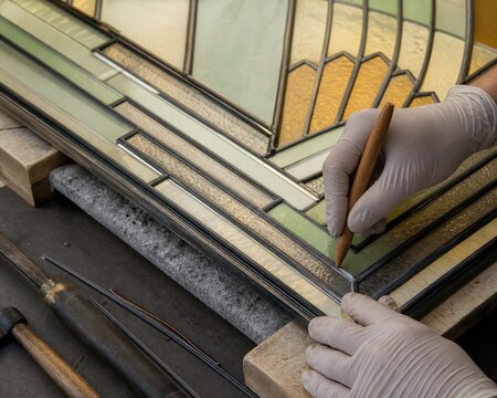 Stained glass restoration hands repairing art deco hotel transom only craft simple leaded historic gloved use small wooden fid