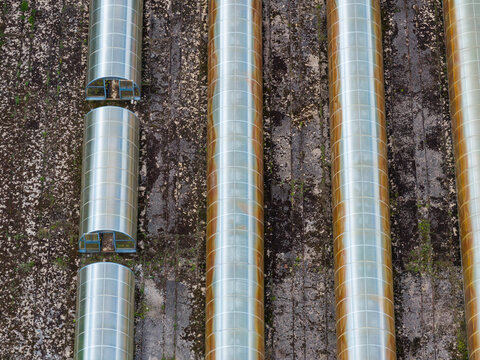 Aerial view of greenhouses at Trakai Voke estate, showing long arched structures with metallic frames and translucent panels in rows over dark soil in Vilnius, Vilnius County, Lithuania.