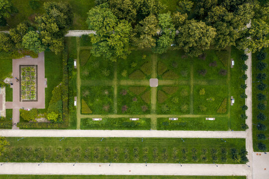 Aerial view of the geometric gardens and manicured lawns of Traku Voke Manor surrounded by lush green trees and gravel pathways in Vilnius, Vilniaus apskritis, Lithuania.