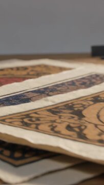 Vertical video: Shifting low camera highlighting deckle edges on wood table, red dot motifs
