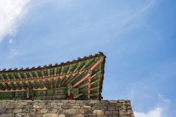 Detailed double eaves with colorful traditional dancheong patterns on a historic fortress pavilion wall in South Korea. © 완수 안