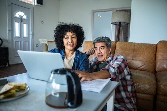 Mature couple managing bills online at home