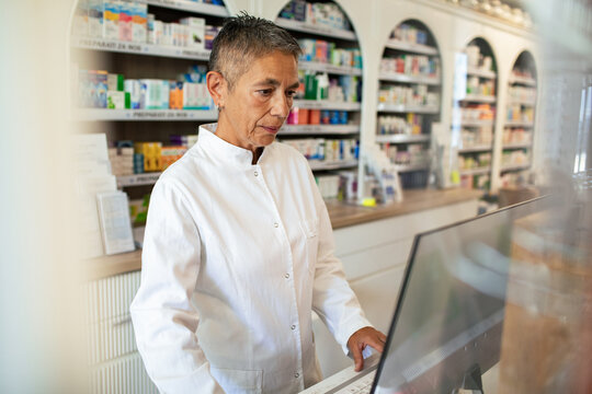 Pharmacist using computer at pharmacy counter