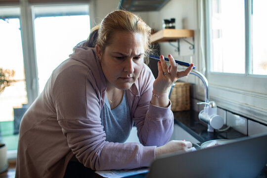 Concerned woman calling about bills in home kitchen