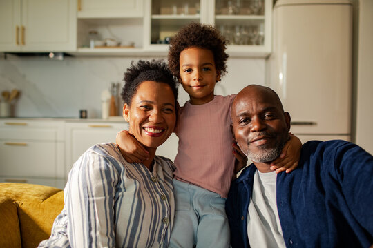 Smiling parents and child hugging in home kitchen