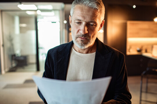 Middle-aged man reviewing document in modern office