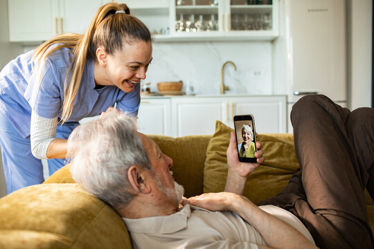 Caregiver helping senior man with video call at home