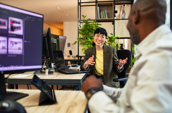 Smiling businesswoman discussing project with colleague in modern open office