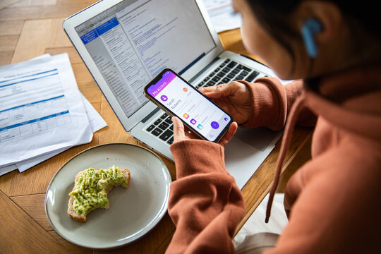 Woman managing mobile banking on smartphone at home office