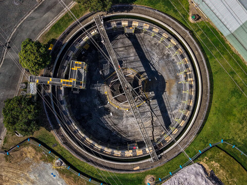 Aerial view of the circular clarifier tank at the Unitywater Brendale Sewerage Treatment Plant, featuring industrial metal structures and green grass in Brendale, Queensland, Australia.