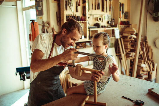 Parent teaching child woodworking in home workshop
