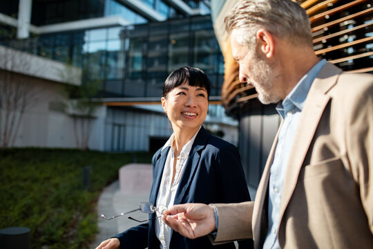Business colleagues walking and talking outside modern office