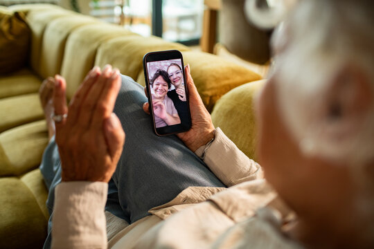 Senior woman waving during video call on smartphone at home