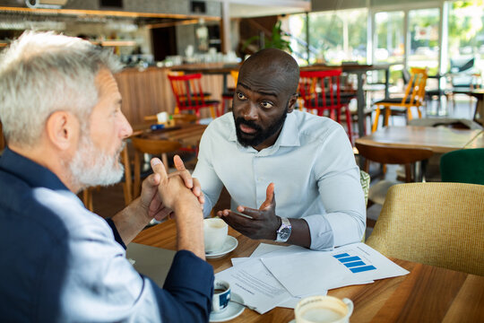 Two businessmen discussing financial report at cafe