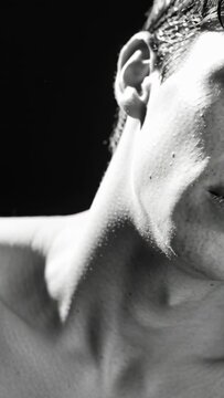 Vertical video: Camera moving closer male model holding gaze, tilting in studio