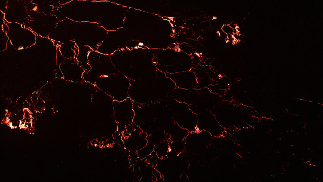 Aerial view of glowing lava flow patterns from an active volcano, showing molten rock cooling into dark crust in Reykjavik, Reykjavikurborg, Iceland.