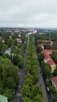 Aerial drone video of Koskelantie in the K&auml;pyl&auml; area of Helsinki, Finland, surrounded by lush green trees and urban residential buildings during summertime.