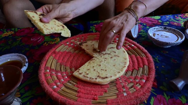 Marrakech, morocco. August 9, 2026. Two people sharing a traditional moroccan flatbread during a meal. Close up on hands breaking a piece of bread to eat with local sauces