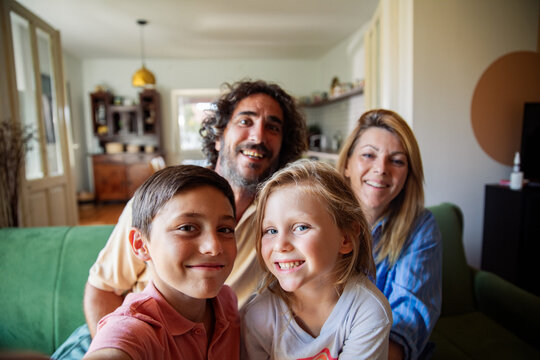 Smiling family with kids taking selfie in living room