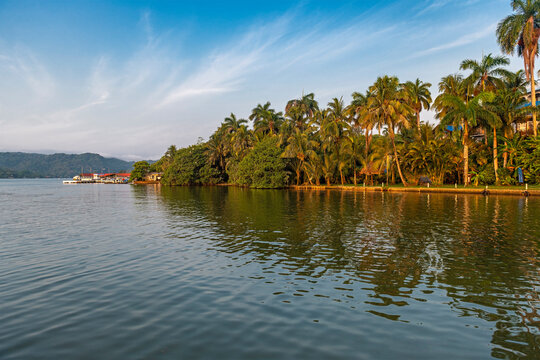 Livingston city at sunrise with palm trees and harbour along Rio Dulce, Guatemala.